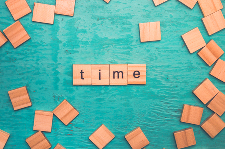 Time word laid out with wooden letters of the alphabet concept on a blue backgroundの写真素材