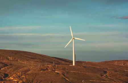 Wind turbine power station among the hills during sunsetの写真素材