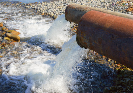 Water flows from the pipe to the sea, closeup of photo