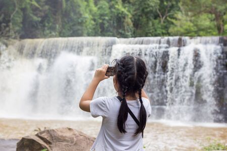 Asian kid with a waterfall in Thailand.の写真素材
