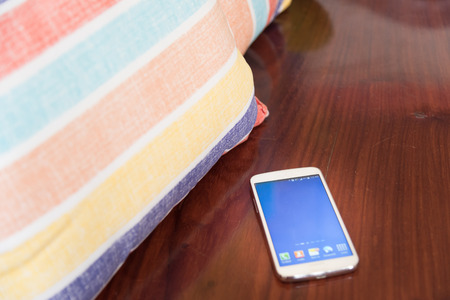 Smart phone on the table beside the pillow.の写真素材