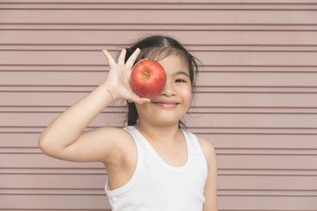Little Asian girl enjoy eat an apple.の写真素材