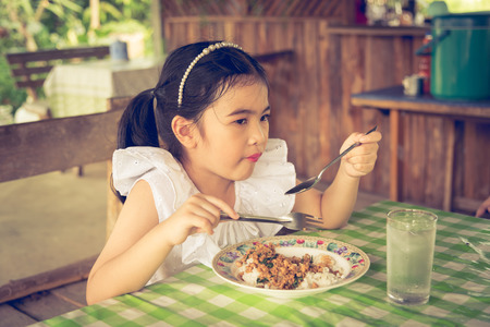 Asian kid girl Eating basil pork in Thailand.の写真素材