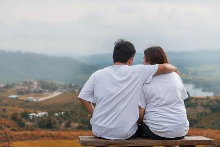 Back view of two sitting on the seat of view and looking at horizon in a bad weather day.の写真素材