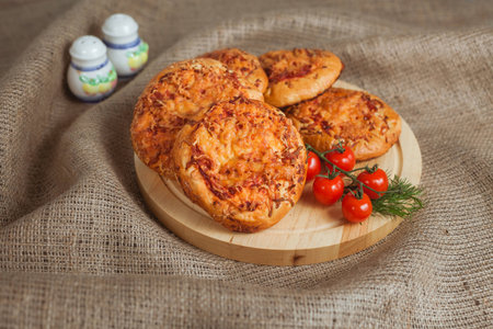 Few little pizzas on the burlap. Two salt-cellars and red tomatos.の写真素材