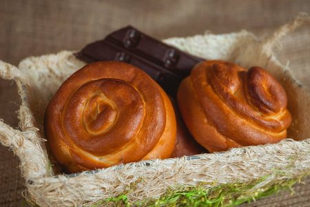Sweet spiral buns in the basket. Little of a chocolate on the background.の写真素材