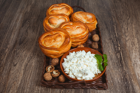 Sweet buns and plate of cottage cheese. Products in a basketの写真素材