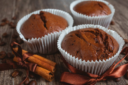 Chocolate muffins in a paper wrapping. Wood table.の写真素材
