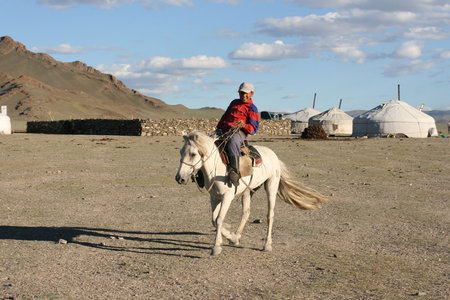 Mongolian boy racing on a horse in front of nomads tent- August 06, 2008. Mongolia
