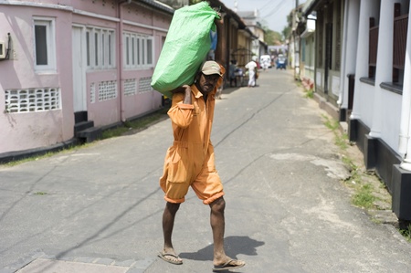 Galle, Sri Lanka - 27th, 2011: Worker with a big packet walking on the streetのeditorial素材