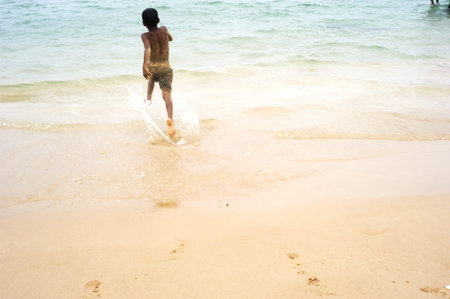 Hikkaduwa, Sri Lanka - February 04, 2011: Sri Lankan boy running on the beach to the ocean.のeditorial素材