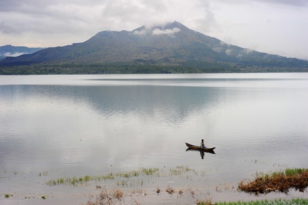 Bali island,Indonesia - April 10,2011: Man fishing in a caldera lake of Batur volcano. Batur is the most active volcano on the popular tourist island of Bali and one of Inondesia's more active ones on Baliのeditorial素材