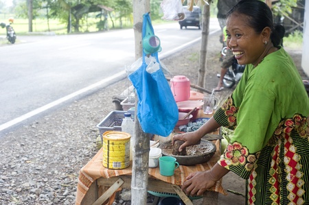 Java,Indonesia - April 21,2011: A smiling woman preparing fast food near the roadのeditorial素材