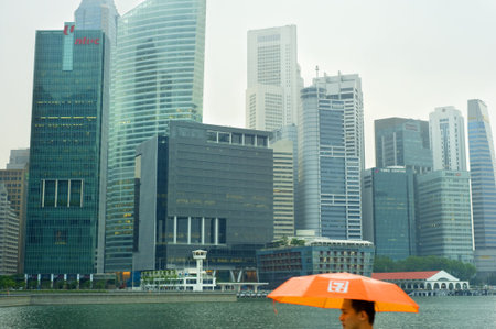Singapore, Republic of Singapore - May 05, 2011: Man with ubrella in the rain in Singapore. Singapore has long been recognised as one of the best cities for business.のeditorial素材
