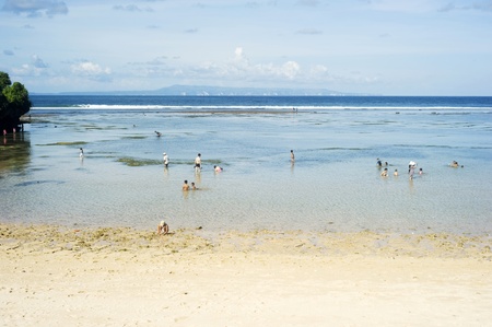 Nusa dua, Bali, Indonesia - April 17, 2011: People swimming in the ocean during tide ebb. Nusa Dua is known as an enclave of large international 5-star resorts in south-eastern Bali.のeditorial素材