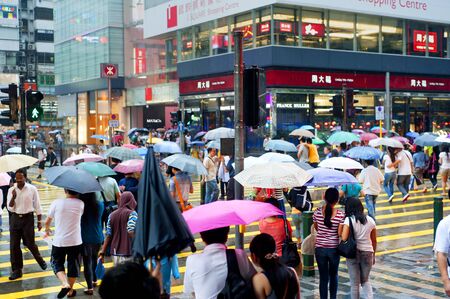 Hong Kong S.A.R. - MAY 20, 2012: People crossing the road in the rain.  With a land mass of 1,104 km and population of 7 million people, Hong Kong is one of the most densely populated areas in the worldのeditorial素材