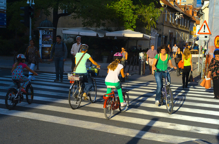 LUJBLJANA, SLOVENIA - SEPTEMBER 9, 2013: Unidentified people crossing street and riding bicycles on the street of Ljubljana. The downtown quarter usually attracts lots of tourists.のeditorial素材