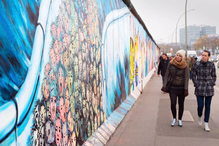 BERLIN, GERMANY - NOV 15, 2014: People walkingat Berlin Wall at East Side Gallery . It's a 1.3 km long part of original Wall which collapsed in 1989 and now is largest world graffiti gallery.のeditorial素材