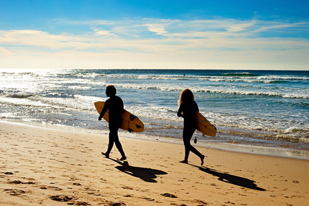 Couple of surfers walking on the ocean beach.  Sagres, Algarve, Portugalの写真素材