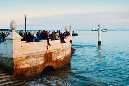 LISBON, PORTUGAL - JAN 10, 2015: People watching sunset at Tagus river embankment in Lisbon,...