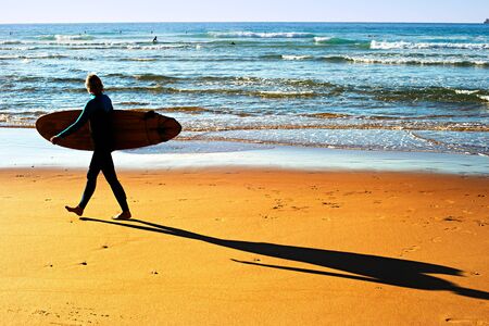 Woman with surfboard walking on the ocean beach. Portugalの写真素材