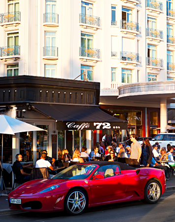 CANNES, FRANCE - SEPT 15 2013: People sitting at a cafe and walking on the street in Cannes. The city is famous for its luxury hotels and restaurantsのeditorial素材