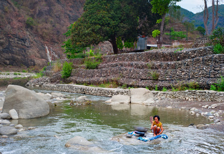 SAGADA, PHILIPPINES - MARCH 25, 2012: Philippines woman washing clothes on the river in...