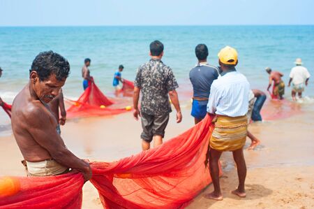HIKKADUWA, SRI LANKA - FEB 19, 2011: Local fisherman pull net from the ocean. Fishing in Sri Lanka is a tough job but this is the way they earn their livingのeditorial素材