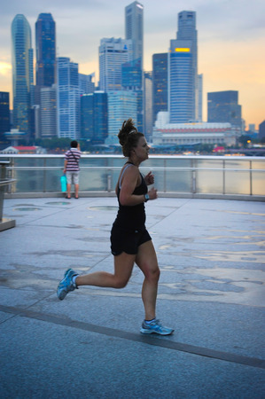 SINGAPORE - MAY 06, 2012: Unidentified woman runnig in front of Singapore downtown in Singapore. Singapore has been recognized as one of the best cities for runners in Asia.のeditorial素材