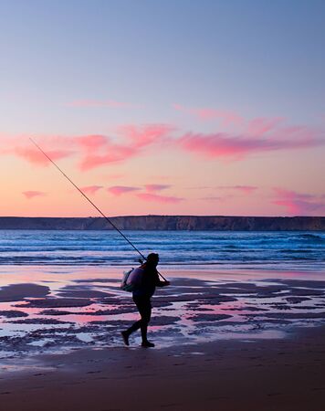 Portuguese fisher walking on the ocean beach at sunset. Portugalの写真素材