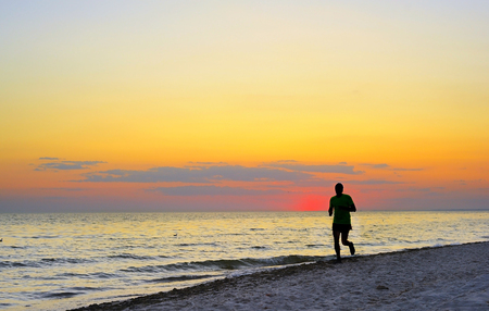 Man jogging on the beach at a beautiful sunset.の写真素材