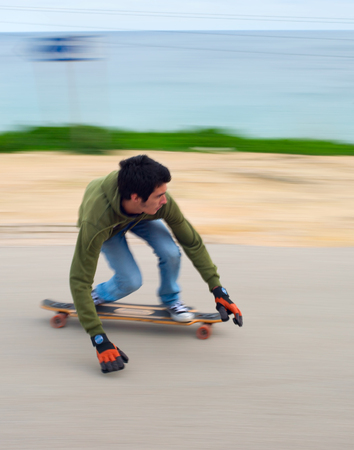 SAGRES, PORTUGAL - DEC 27, 2014: Blured motion of teenagers on a longboard going down the hill. Longboard is a type of sports equipment somewhat similar to a skateboard, but in a certain way "longer".のeditorial素材