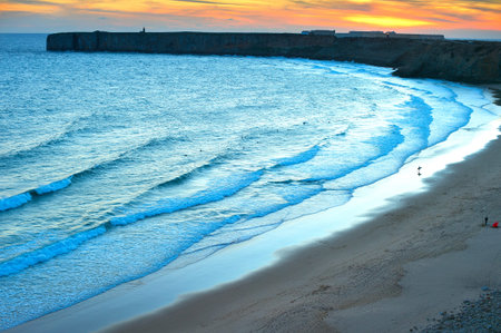 View of surfing spot at sunset with silhouette of a walking surfer