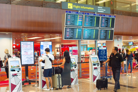 SINGAPORE - JANUARY 13, 2017: Passengers at self check-in kiosk near information board in Changi Airport. Changi Airport serves more than 100 airlines operating 6,100 weekly flightsのeditorial素材