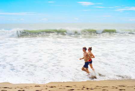 BALI ISLAND, INDONESIA - JAN 18, 2017: Beautiful couple running on the ocean beach on Bali island, Indonesia. Bali island is the famous tourists destination.のeditorial素材