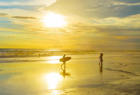 Surfer walking on the beach with surfboard at sunset. Bali island, Indonesiaの写真素材