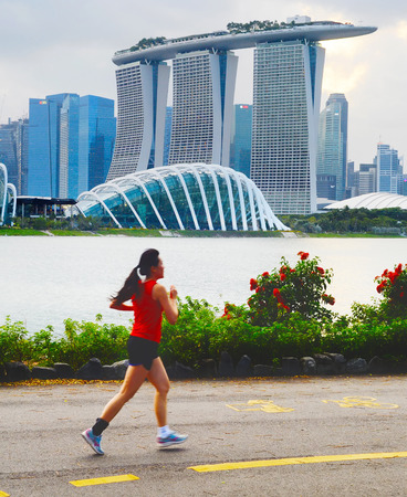 SINGAPORE - FEB 16, 2017: Beautiful young chinese woman running in Singapore bay at sunset. Motion blur.のeditorial素材