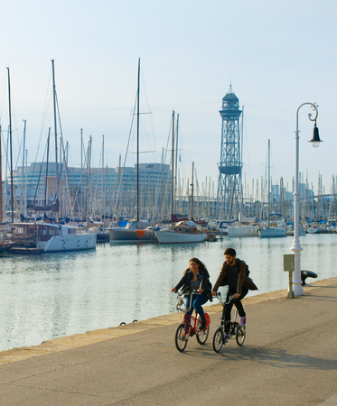 BARCELONA, SPAIN - NOV 03. 2016: Couple riding bicyles at Port Well Barcelona. Port Vell is a waterfront harbor in Barcelonaのeditorial素材
