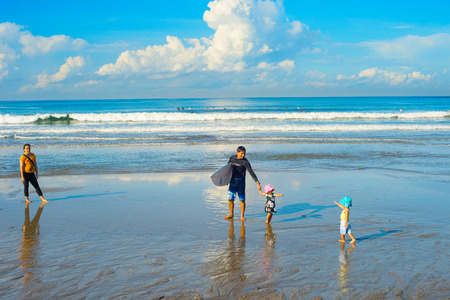BALI iSLAND, INDONESIA - MARCH 04, 2017: Surfers family with children on the beach. Bali island is the world famous surfing destinationのeditorial素材