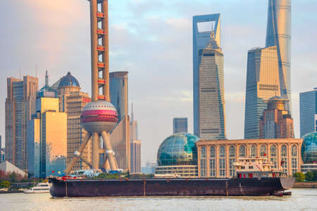 Barge by sunset Shanghai skyline with famous tv tower and skyscrapers of modern architecture, China