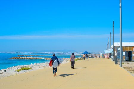 COSTA DA CAPARICA, LISBON, PORTUGAL - SEPTEMBER 17, 2018: People walking by seaside promenade in the sunny summer day. Costa de Caparica is the famous tourist destinationのeditorial素材