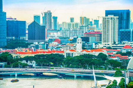 Singapore metropolis cityscape, tourist boats by green quay, bridges and construction of modern district in backgroundの写真素材