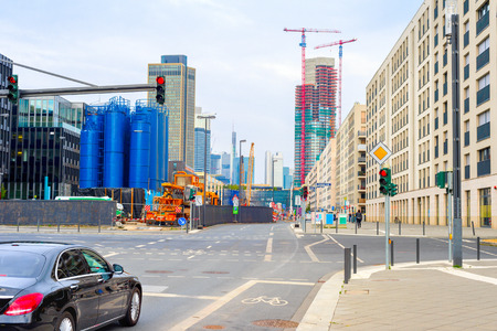 Frankfurt urban cityscape with car on crossroad, industrial plant building, cranes by skyscraper construction site in background, Germanyの写真素材