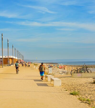 COSTA DA CAPARICA, LISBON, PORTUGAL - SEPTEMBER 17, 2018: People walking by seaside promenade in the sunny summer day. Costa de Caparica is the famous tourist destinationのeditorial素材