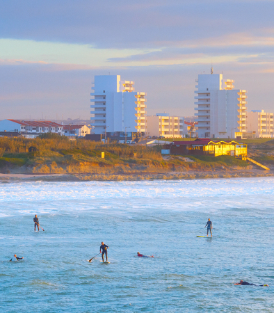 Aerial view of paddle surfing and surfers by Atlantic coast, scenic seascape with Baleal town in sunset light, Portugalの写真素材