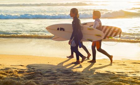 PENICHE, PORTUGAL - OCTOBER 20, 2018: Three boys in wetsuits with surfboards at ocean coast, Peniche, Portugalのeditorial素材
