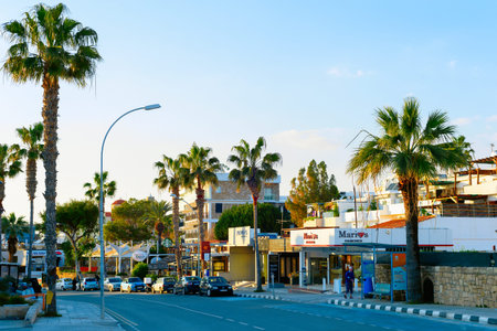 PAPHOS, CYPRUS -FEBRUARY 13, 2019: Cityscape of Paphos downtown street with palms, shops and parked...