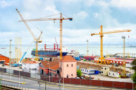 Ship in city port, cranes and heavy freight machinery equipment at pier of Tagus river. Lisbon, Portugalの写真素材