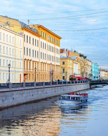 Downtown cityscape, Griboedova street with bridge over canal in sunset light, sightseeing tourists on cruise boat, Saint Petersburg, Russiaの写真素材