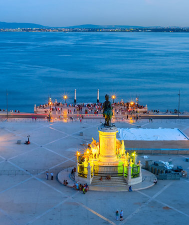 Aerial view to the illuminated Commerce square of Lisbon with statue of King Jose I, skyline with boat at Tagus river and city lightsのeditorial素材